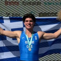Ο Ιάσονας Μουσελίμης πανηγυρίζει στο βάθρο του Παγκοσμίου Πρωταθλήματος Beach Sprint της Κίνας με το ασημένιο μετάλλιο, κρατώντας την ελληνική σημαία.