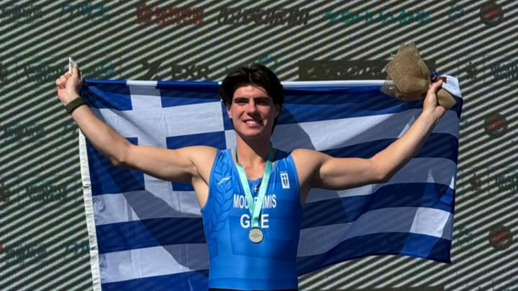 Ο Ιάσονας Μουσελίμης πανηγυρίζει στο βάθρο του Παγκοσμίου Πρωταθλήματος Beach Sprint της Κίνας με το ασημένιο μετάλλιο, κρατώντας την ελληνική σημαία.